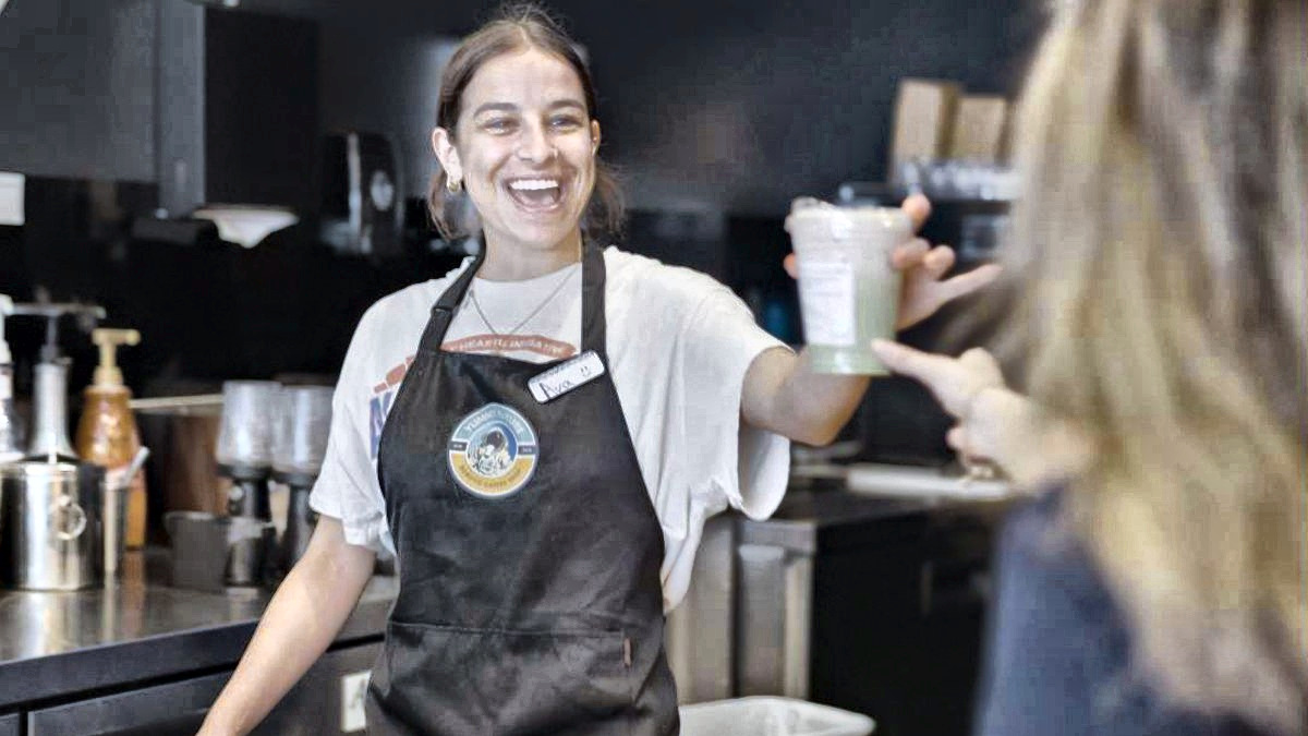 A barista handing a drink to a customer across the counter