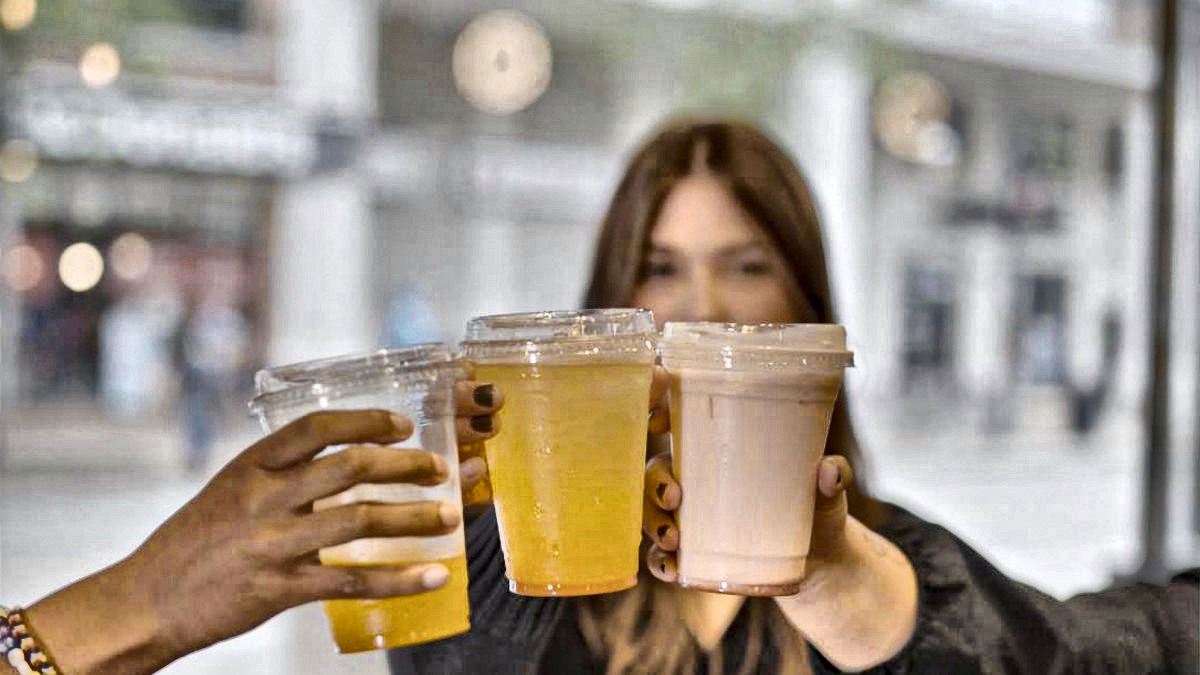 Three friends toasting with Yummy Future drinks outside a store